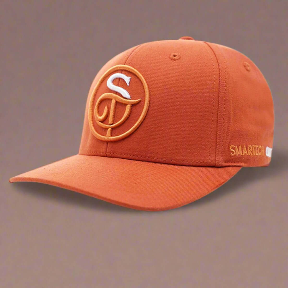 An Orange Cotton Classic Baseball Cap from Smartech Outfit features a white and orange embroidered logo with the letters "S" and "D" intertwined on the front. The side of this premium cap highlights the words "SMARTECH" alongside another partially visible logo, ensuring brand quality throughout.